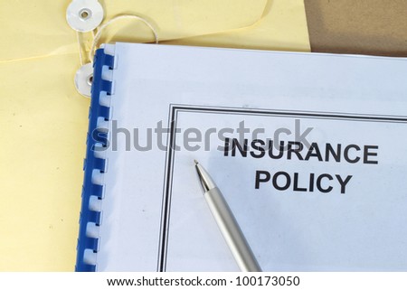 insurance policy folder on desk in office with pen and manila envelop