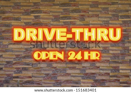 Drive thru neon signage in a brick wall.