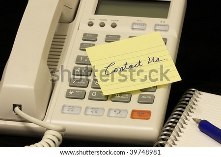 yellow message note over a phone with  a writing contact us!