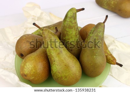 A still life of organic Conference pears with a green back drop.