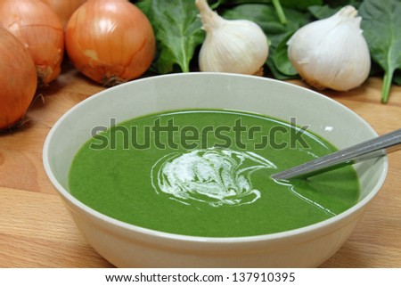 A nutritious bowl of fresh spinach soup, with some of the ingredients in the background.