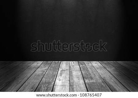 Empty room with black concrete wall an wooden floor illuminated from above, empty interior
