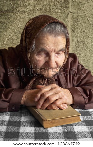 Elderly woman holds bible and pray.