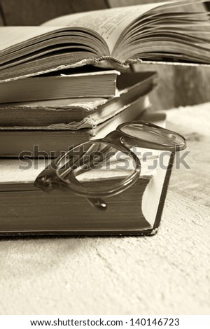 Old books with reading glasses. Selective focus on glasses.