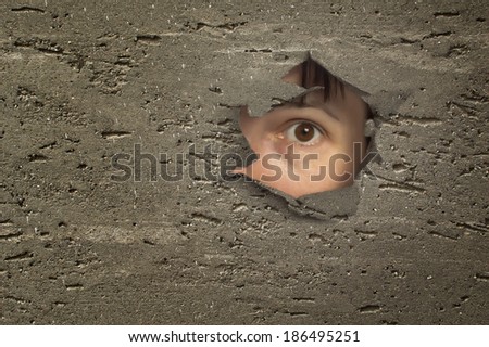 Eye looking through a hole in wall.