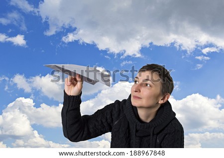Young caucasian girl starts paper plane in blue sky