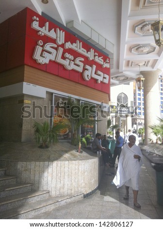 MECCA, SAUDI ARABIA - JUNE 3 : A muslim pilgrim walk by a Kentucky Fried Chicken (KFC) shop in Makkah on June 3, 2013 in Makkah. KFC Saudi is owned by Americana Group.