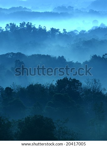 Misty morning of hilly area with ray of light.
