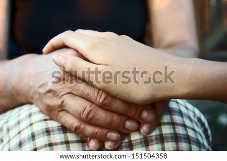Hand of young girl comforting elderly hands in support close up