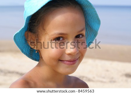 stock photo Smiling preteen girl on a beach in blue background