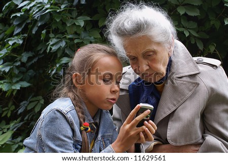 Grand daughter and her grand mother dial mobile phone