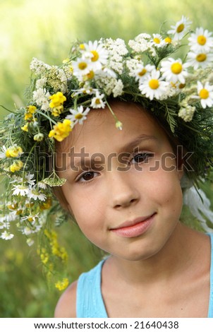 stock photo Cheerful preteen girl in field flower garland on green grass 