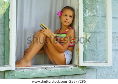 stock photo Preteen girl with a book sitting in window