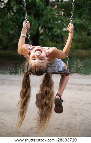 stock photo Preteen girl having fun on a swing on playground