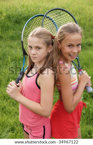 stock photo Happy preteen girls in sport outfits with tennis rackets on 