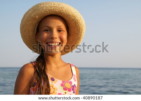Preteen girl in straw hat enjoying sun-bath on sea beach