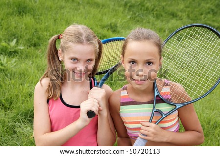 stock photo Happy preteen girls in sport outfits with tennis rackets on