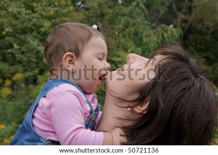 Happy baby daughter kissing mother outdoors