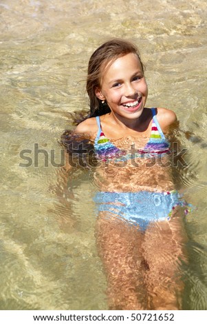 stock photo Cheerful preteen girl swimming in sea