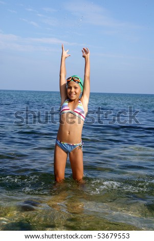 stock photo Preteen girl in diving outfit playing with water on sea beach