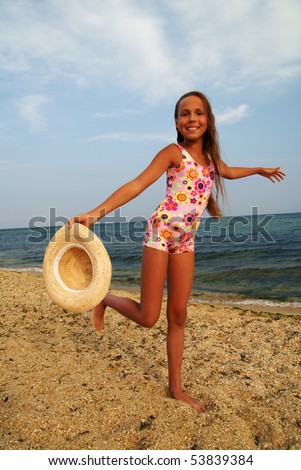  Cheerful preteen girl with straw hat enjoying sunbath on sea beach