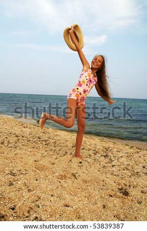 stock photo Cheerful preteen girl with straw hat running on sea beach