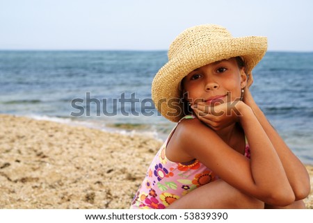 Portrait of cheerful preteen girl in straw hat enjoying sun-bath on sea beach