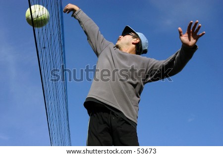 Young man hitting the ball over the net