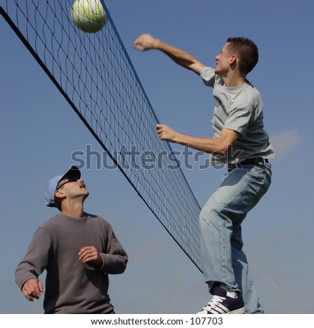 Young men hitting the ball over the net