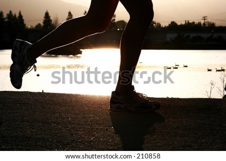 Woman jogging along a river at sunset