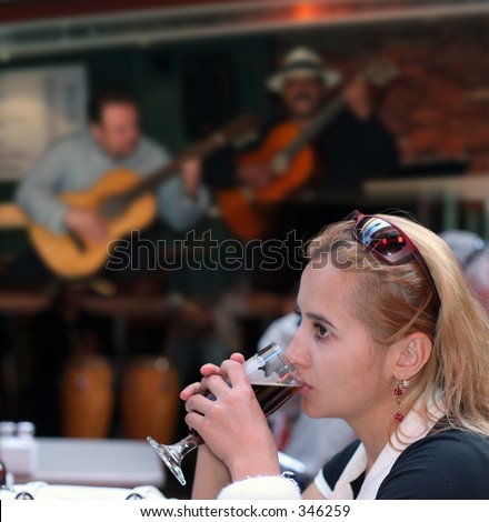Girl drinking beer alone in a restaurant with live music