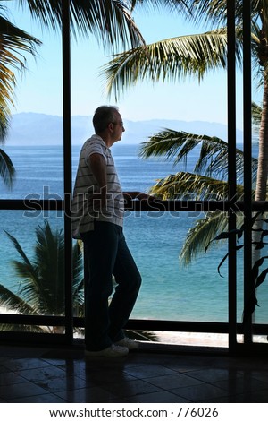Man standing by the window in a tropical resort