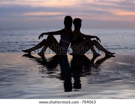 Women and their reflections in a pool by the ocean