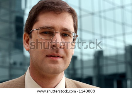 Young businessman with office building in the distance.
