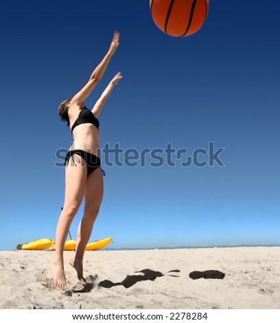 Girl playing with giant basketball on the beach