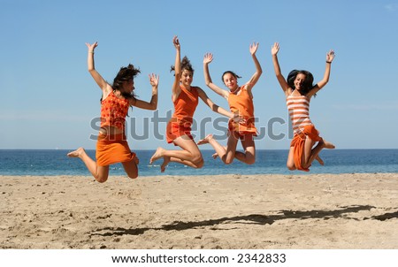 Four girls in orange clothes jumping on the beach