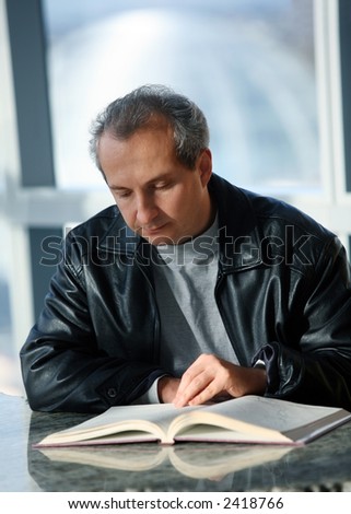 Mature man reading a book in the library