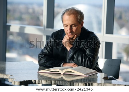 Mature man reading a book in the library