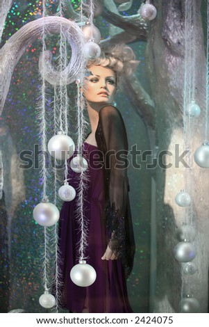 Mannequin in the window set up with a winter theme. Focus is on the ornaments.