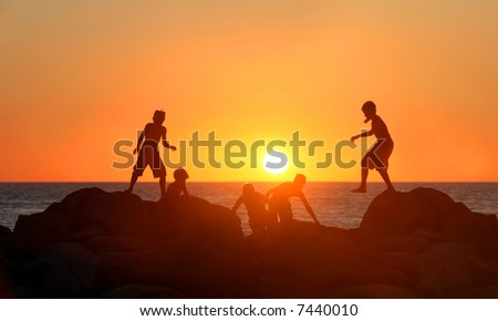 Boys playing on the beach at sunset