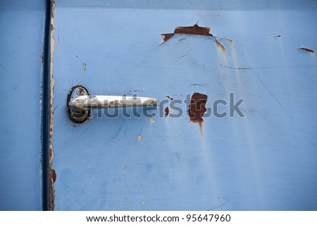 Rusted blue  truck door with doorknob.