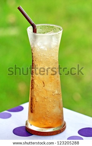 Glass of iced apple tea on colorful table
