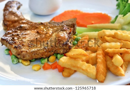 Steak with mix vegetable and fries. Pork chop steak.