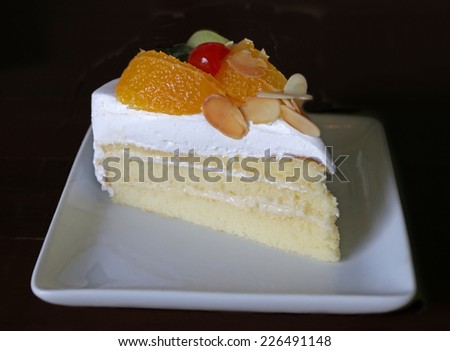 Mixed tropical fruit cake with white cream on black background