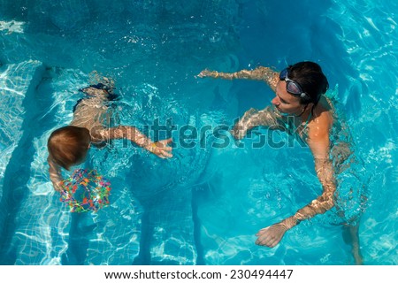 Mother and son learning to swim in the pool. the child dives
