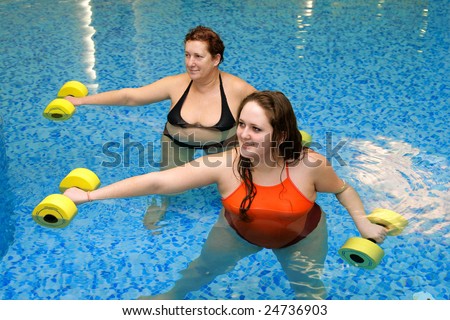 Adult fat  women and young fat woman on group aqua aerobics training in water with dumbbells