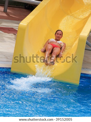 Pretty brunette woman riding down a waterslide\
\
in aqua park