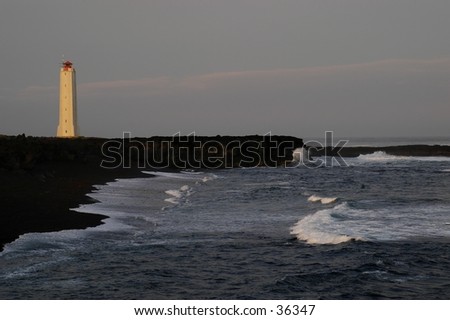 Lighthouse in the evening sun.  Waves hitting the beach.  Plenty of space for text.