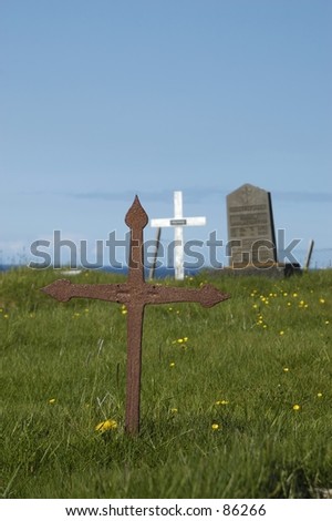 3 different crosses on a meadow.  Selective focus with focus on the rusty cross in the foreground.