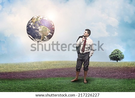 A man in the middle of a meadow looks at the earth and thinks (Elements of this image furnished by NASA)